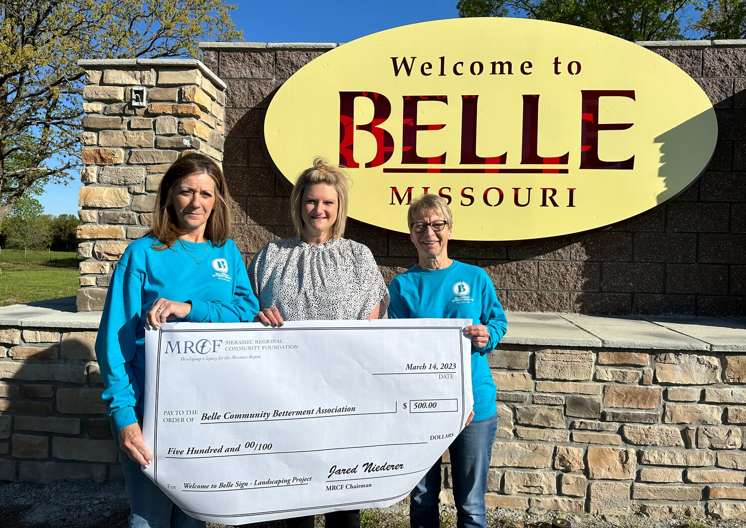 Belle Community Betterment Association members Vicki Nelson (left), Ashley Harris and Barb Schaller pose for a picture at the Welcome to Belle Sign with the $500 Meramec Regional Community Foundation “check” for the BCBA’s landscaping project. The Belle Community Betterment Association is one of three organizations to receive a 2023 community grant from MRCF.